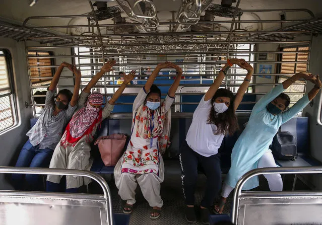 Commuters take part in a yoga session as they travel in a local train to mark International Yoga Day  in Mumbai, India Monday, June 21, 2021, (Photo by Rafiq Maqbool/AP Photo)