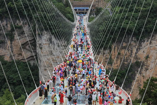 This aerial photo taken on June 20, 2021 shows people walking on a glass-bottomed skywalk in Zhangjiajie, in China's central Hunan province. (Photo by AFP Photo/China Stringer Network)