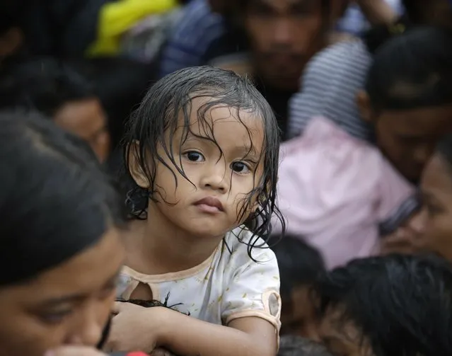 A child waits with fellow typhoon survivors as they line up in the hopes of boarding an evacuation flight on a C-130 military transport plane Tuesday, November 12, 2013, in Tacloban, central Philippines. (Photo by Bullit Marquez/AP Photo)