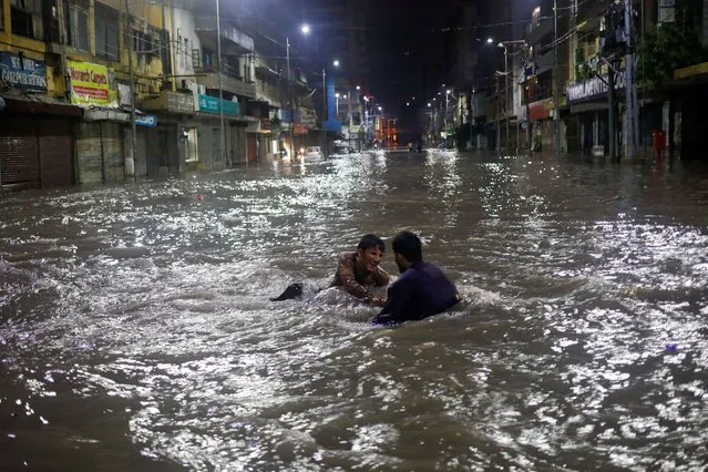 Residents play on a flooded street, following heavy rains during the monsoon season in Karachi, Pakistan on July 24, 2022. (Photo by Akhtar Soomro/Reuters)