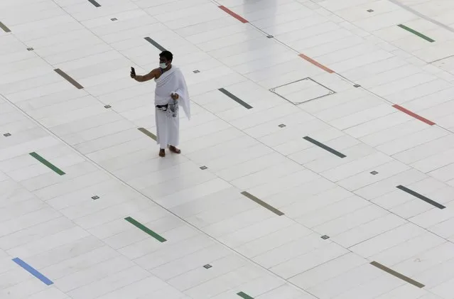 A Muslim pilgrim takes a selfie at the Grand Mosque, as he wears a mask and stands on social distancing signs, a day before the annual hajj pilgrimage, Saturday, July 17, 2021. The pilgrimage to Mecca required once in a lifetime of every Muslim who can afford it and is physically able to make it, used to draw more than 2 million people. But for a second straight year it has been curtailed due to the coronavirus with only vaccinated people in Saudi Arabia able to participate. (Photo by Amr Nabil/AP Photo)