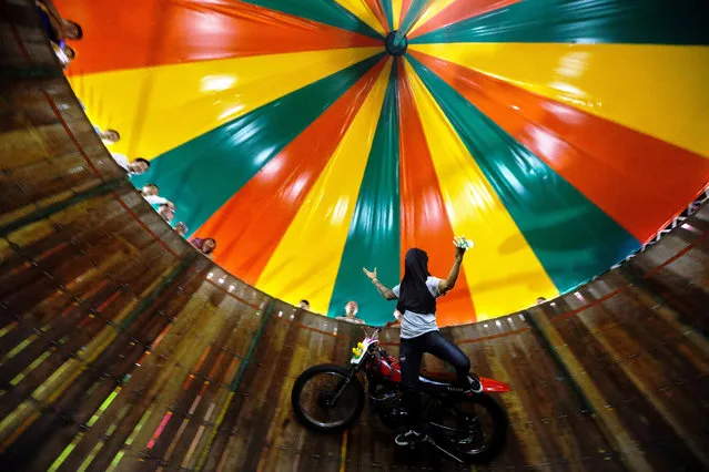 A stuntman covering his face rides a motorcycle inside the Well of Death attraction during a fair in Bangkok, Thailand on November 27, 2018. (Photo by Athit Perawongmetha/Reuters)