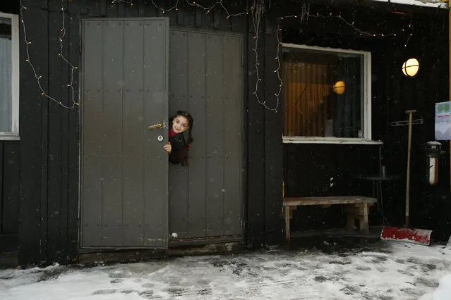 In this photo taken Tuesday, February 2, 2016, Afghan asylum seeker Helanar Nawabi, pokes her head round the door of the main entrance of her in temporary accommodation at the Altnes camp on the island of Seiland, northern Norway. (Photo by Alastair Grant/AP Photo)
