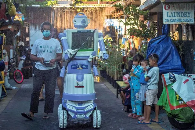 Aseyan, who goes by one name only, operates a disinfection robot named Delta, which he created from recycled household goods, at a neighbourhood in Surabaya on July 28, 2021. (Photo by Juni Kriswanto/AFP Photo)