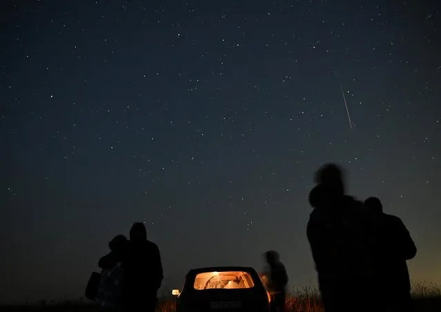 People watch as meteor streaks in the night sky during the annual Perseid meteor shower in the Siberian town of Yeniseysk in the Krasnoyarsk Region, Russia on August 12, 2023. (Photo by Alexey Malgavko/Reuters)