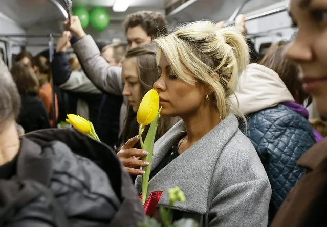 Female metro passengers hold flowers presented to them by metro workers, prior to International Women's Day in Kiev, Ukraine, 02 March 2016. (Photo by Sergey Dolzhenko/EPA)