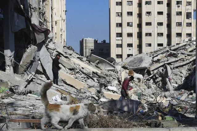Palestinians walk through destruction from the Israeli bombardment in the Nusseirat refugee camp in Gaza Strip, Friday, January 19, 2024. (Photo by Adel Hana/AP Photo)