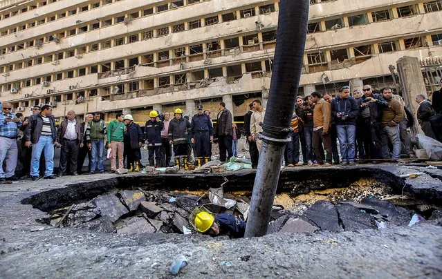 A firefighter checks a crater made by a blast at the police headquarters in downtown Cairo, Egypt, on January 24, 2014. A car bomb struck the main police headquarters Friday in the heart of Cairo, killing several people in a hugely symbolic attack on the eve of the third anniversary of the 2011 uprising that toppled long time autocratic ruler Hosni Mubarak. (Photo by Amr Nabil/Associated Press)