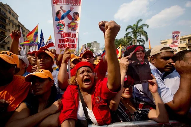 A supporter of Venezuela's President Nicolas Maduro cheers as another holds a picture of Venezuela's late President Hugo Chavez during a May Day rally in Caracas, Venezuela, Friday, May 1, 2015. (Photo by Fernando Llano/AP Photo)