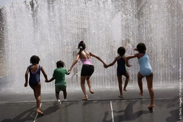 A group of children run into a fountain on the South Bank