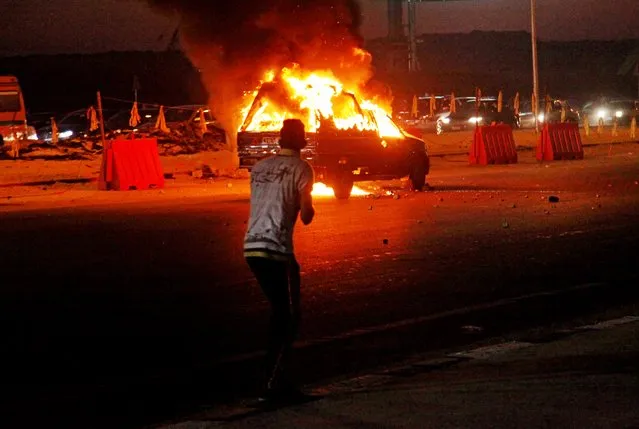 In this Sunday, February 8, 2015 file photo, a man looks at a burning vehicle during a riot outside an air defense stadium in a suburb east of Cairo, Egypt. At least 22 soccer fans were crushed to death outside an air defense stadium in Cairo after police fired tear gas to break up the crowd waiting in a fenced, narrow corridor to watch. (Photo by Ahmed Abd El-Gwad/AP Photo/El Shorouk Newspaper)
