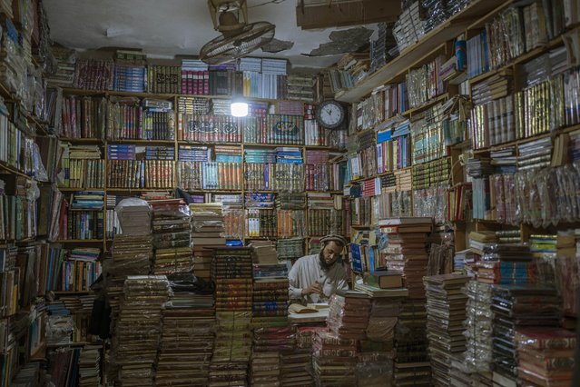 A bookshop owner repairs a book in Herat, Afghanistan, Monday, November 22, 2021. (Photo by Petros Giannakouris/AP Photo)