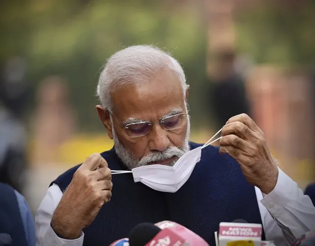 Indian Prime Minister Narendra Modi, removes his mask before addressing the media on the opening day of the winter session of Parliament in New Delhi, India, Monday, November 29, 2021. India’s parliament on Monday repealed a set of controversial agriculture laws that inflamed tens of thousands of farmers, whose year-long protest has posed one of the biggest challenges to Prime Minister Narendra Modi’s administration. (Photo by Manish Swarup/AP Photo)