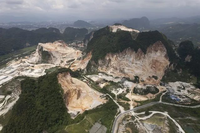 Deforestation surrounds massive limestone quarries cut into the mountains of Ipoh, Perak state Malaysia, Friday, November 5, 2021. Deforestation affects the people and animals where trees are cut, as well as the wider world and in terms of climate change, and cutting trees both adds carbon dioxide to the air and removes the ability to absorb existing carbon dioxide. World leaders are gathered in Scotland at a United Nations climate summit, known as COP26, to push nations to ratchet up their efforts to curb climate change. (Photo by Vincent Thian/AP Photo)