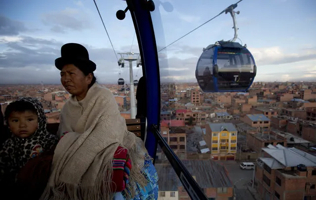 In this Friday, March 3, 2017 photo, a woman and a child ride a cable car that interconnects the city El Alto, Bolivia. The cable car system is the world's highest, some 4 thousand meters above sea level. (Photo by Juan Karita/AP Photo)