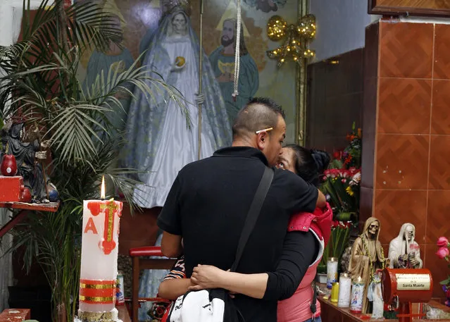 In this Feb. 26, 2017 photo, devotees of the Death Saint or “Santa Muerte” embrace during a service at Mercy Church in Mexico City's Tepito neighborhood. Devotees believe the folk saint can protect against assaults, accidents, gun violence, and all types of violent death. (Photo by Marco Ugarte/AP Photo)