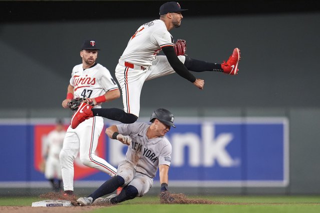 Minnesota Twins shortstop Carlos Correa jumps after outing New York Yankees' Anthony Volpe, bottom, to make a double play off a groundout hit by Juan Soto during the ninth inning of a baseball game Wednesday, May 15, 2024, in Minneapolis. (Photo by Abbie Parr/AP Photo)