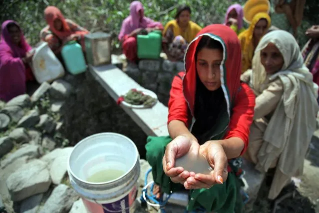 An Indian villager woman shows unclean drinking water after collecting it from an almost dried up well at Padal village of Samba district, some 40 km from Jammu, the winter capital of Kashmir, India, 27 April 2016. According to reports, 10 villages in Samba district of Jammu and Kashmir are drought-affected. The drought has been ongoing for the past two months in the region, forcing women and children to walk miles to fetch water. (Photo by Jaipal Singh/EPA)