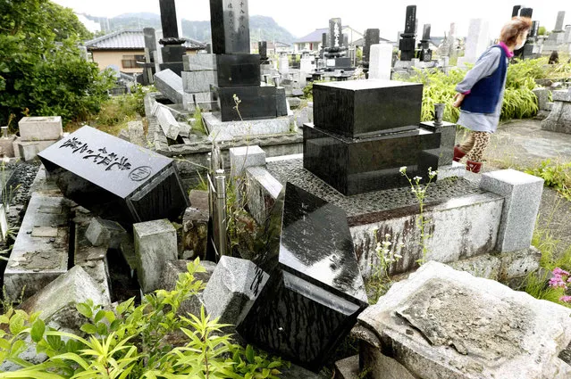 A woman walks past collapsed gravestones in Murakami, Niigata prefecture, northwestern Japan, Wednesday, June 19, 2019, after an earthquake. The powerful earthquake jolted northwestern Japan late Tuesday, prompting officials to issue a tsunami warning along the coast which was lifted about 2 ½ hours later. (Photo by Yusuke Ogata/Kyodo News via AP Photo)