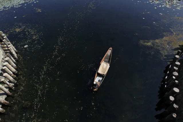 A Kashmiri boatman selling traditional floor mats rows his boat on the waters of Dal Lake in Srinagar October 15, 2011. (Photo by Fayaz Kabli/Reuters)