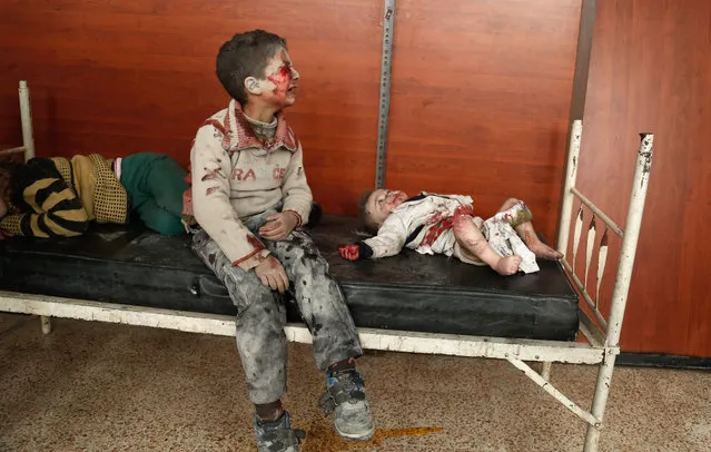 Wounded Syrian children cry as they wait to receive treatment following a reported air strike on the rebel-controlled town of Hammuriyeh, in the eastern Ghouta region on the outskirts of the capital Damascus, on March 25, 2017. (Photo by Abdulmonam Eassa/AFP Photo)