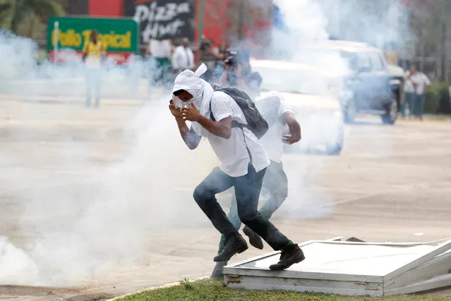 Students cover their faces from tear gas fired by police during a protest to demand the government to repeal a law that requires high school seniors to teach at least two people to read and write, as part of a graduation programme in Tegucigalpa, Honduras, May 4, 2016. (Photo by Jorge Cabrera/Reuters)