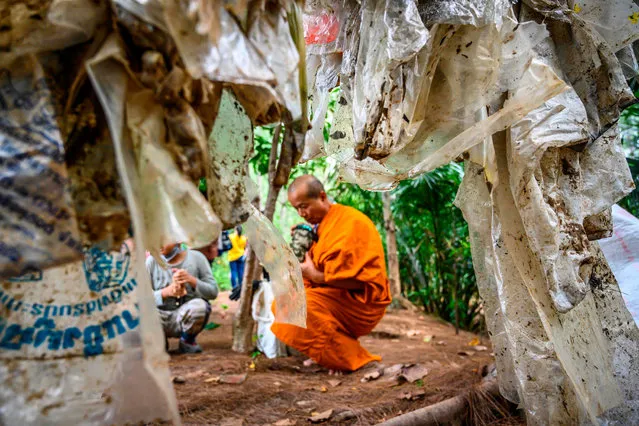 A Buddhist monk sits next to used plastic bags at Khung Bang Kachao Urban Forest and beach collected as part of the Trash Hero initiative in Bangkok on August 25, 2019. Hundreds of people gathered on the bank of the Chao Praya river to clean it from the tons of plastic waste carried by the current. (Photo by Mladen Antonov/AFP Photo)