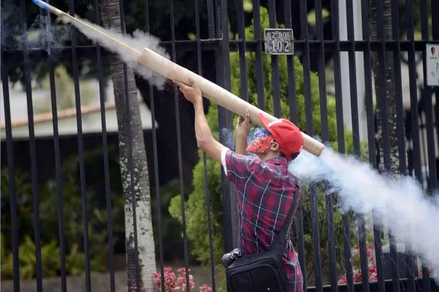 An anti-government demonstrator fires a homemade rocket during confrontations with riot police during a protest against the government of President Nicolas Maduro in Caracas  on May 14, 2014. About 80 demonstrators were arrested during a protest as they request the immediate release of youth detained in recent days. (Photo by Gerardo Caso/AFP Photo)