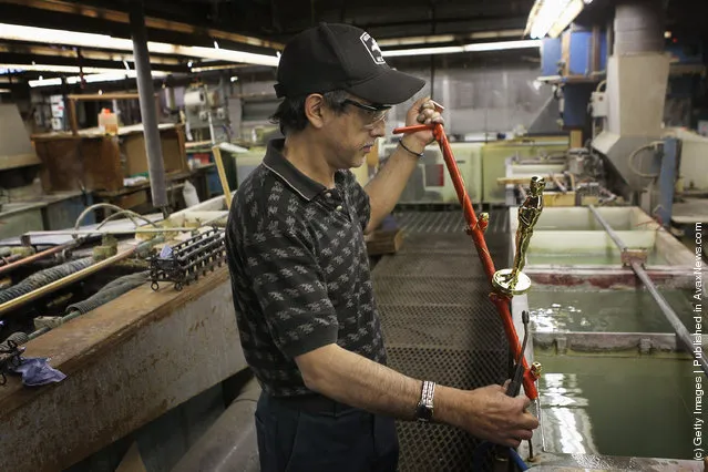 Manuel Nunez demonstrates the plating process for an Oscar statuette at R.S. Owens & Company