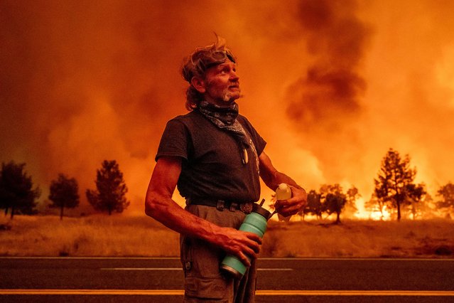 Grant Douglas pauses to drink water while evacuating as the Park Fire jumps Highway 36 near Paynes Creek in Tehama County, Calif., Friday, July 26, 2024. (Photo by Noah Berger/AP Photo)