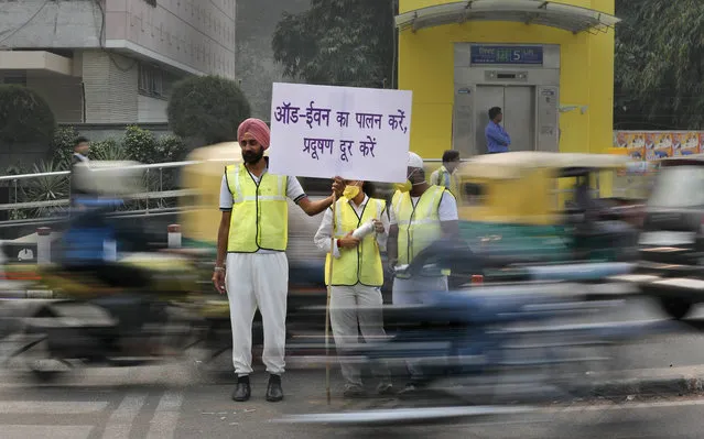 Volunteers wear pollution masks as they stand at a busy crossing with the banner saying obey odd and even, remove pollution, in New Delhi, India, Monday, November 4, 2019. (Photo by Manish Swarup/AP Photo)