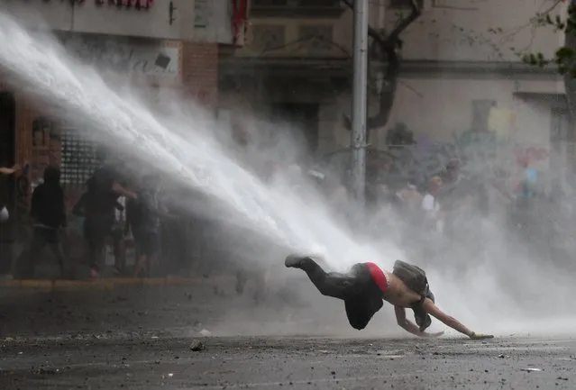 A demonstrator dives to the ground from a water cannon during a protest against Chile's government in Santiago, Chile on November 11, 2019. (Photo by Ivan Alvarado/Reuters)