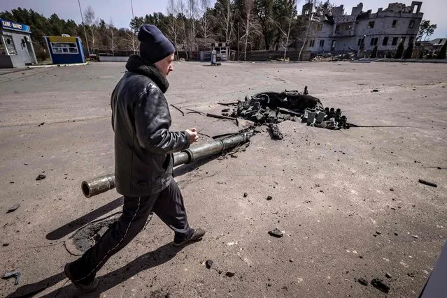 A man walks next to a turret of a destroyed tank near the village of Zalissya, northeast of Kyiv, on April 14, 2022, amid Russia's military invasion launched on Ukraine. (Photo by Fadel Senna/AFP Photo)