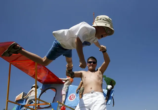 A man swings a boy around during preparations before the Red Bull Flugtag Russia 2015 competition in Moscow, Russia, July 26, 2015. (Photo by Sergei Karpukhin/Reuters)
