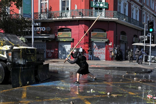 A person reacts in front of a police vehicle as demonstrators clash with riot police during a May Day rally in Santiago, Chile on May 1, 2023. (Photo by Pablo Sanhueza/Reuters)