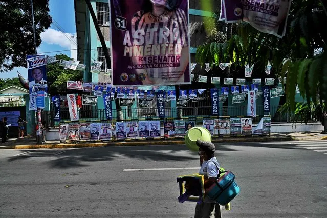 A man walks next to candidate posters ahead of the general elections, in Manila on May 4, 2022. (Photo by Chaideer Mahyuddin/AFP Photo)