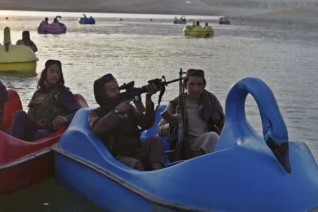 In this photograph taken on September 28, 2021 Taliban fighters ride on paddle boats at Qargha Lake on the outskirts of Kabul. “This is Afghanistan!” a Taliban fighter shouts on the pirate ship ride at a fairground in western Kabul, as his armed comrades cackle and whoop on board the rickety attraction. (Photo by Wakil Kohsar/AFP Photo)