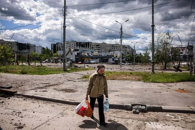 A woman carries bags with food while she walks in the Saltivka district, northern Kharkiv, on May 17, 2022, on the 83rd day of the Russian invasion of Ukraine. Ukraine said on late May 15, 2022 its troops have regained control of territory on the Russian border near the country's second-largest city of Kharkiv, which has been under constant fire since Moscow's invasion began. (Photo by Dimitar Dilkoff/AFP Photo)
