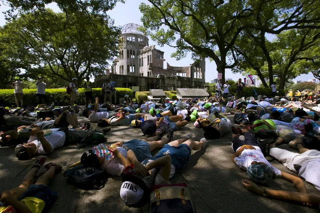 Children perform a die-in in front of the Atomic Bomb Dome in Hiroshima, western Japan, August 5, 2015. (Photo by Thomas Peter/Reuters)