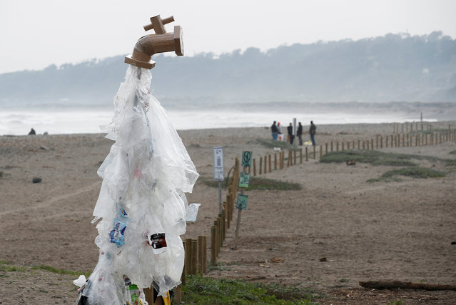 A water tap made out of cardboard and inspired by the installation of Canadian artist Ben Von Wong's faucet leaking plastics is pictured on a beach to raise awareness about plastic pollution during a clean-up action, in Concon, Chile, on August 16, 2024. (Photo by Rodrigo Garrido/Reuters)