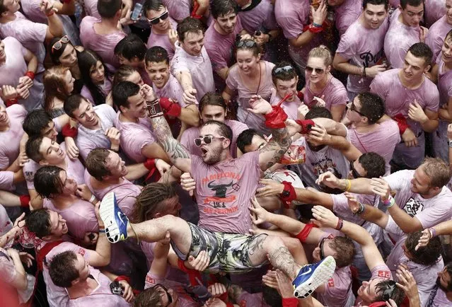 Revelers in beverage stained white t-shirts celebrate just after the rocket fire or “Txupinazo” marked the start of the Festival of San Fermin (or Sanfermines) in Pamplona, Spain, 06 July 2014. The annual nine day long running-with-the-bulls fiesta commemorates St. Fermin, Pamplona's patron saint. (Photo by Jesus Diges/EPA)