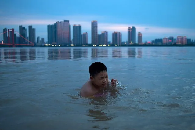 This picture taken on July 5, 2017 shows a youth swimming in the Yangtze River along the River Beach Park in Wuhan, Hubei Province after heavy rains caused the water levels to rise. Heavy rains and windstorms caused floods and landslides in several cities in Hubei, resulting in the deaths of six people. (Photo by AFP Photo/Stringer)