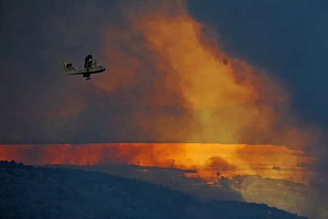 A firefighting aircraft flies over areas burnt by wildfires around Split, Croatia, 18 July 2017. Croatian firemen try put the wildfires under control along the Adriatic coast that has damaged and destroyed some houses in villages around the city of Split. (Photo by EPA/Stringer)