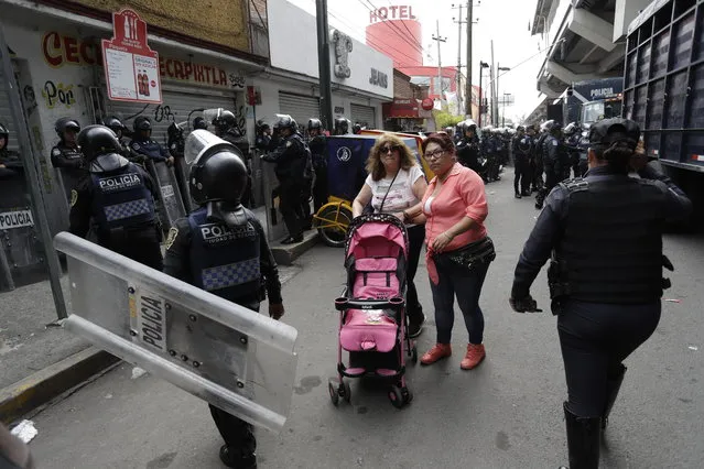Women make their way past police surrounding the Noplera metro after the suspected leader of a drug gang and seven others were killed, according to the Navy, in the Tlahuac neighborhood of Mexico City, Thursday, July 20, 2017. In a statement Thursday, the Navy said a gang of street-level drug dealers operated in the Tlahuac and Iztapalapa districts on the city's south and east sides, where it dealt drugs, as well as carried out kidnappings, extortion and murder. (Photo by Rebecca Blackwell)/AP Photo)