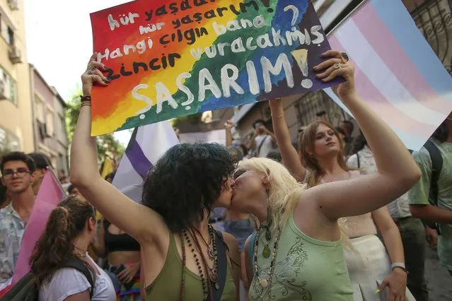 Two women kiss as they hold up a placard that reads in Turkish: “I live free. Who's the fool who will put me in chains? I would be shocked” during the LGBTQ Pride March in Istanbul, Turkey, Sunday, June 26, 2022. Dozens of people were detained in central Istanbul Sunday after city authorities banned a LGBTQ Pride March, organisers said. (Photo by Emrah Gurel/AP Photo)