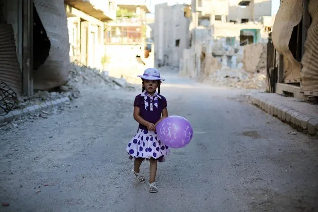A Syrian girl walks amidst destruction during an activity organised by a charity group in Jobar, a rebel-held district on the eastern outskirts of the capital Damascus, ahead of Eid al-Fitr holyday in the war-torn country on July 5, 2016. More than 280,000 people have been killed since Syria's conflict began in March 2011 with protests demanding Assad's ouster. Muslims worldwide celebrate Eid al-Fitr marking the end of the fasting month of Ramadan. (Photo by Amer Almohibany/AFP Photo)