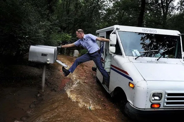 Honorable Mention, Feature. Photo by Michael Ciaglo:  Dave Jackson closes a mailbox with his foot after delivering the mail to a home surrounded on three sides by a flooded Cheyenne Creek in Colorado Springs. (Photo by Michael Ciaglo)