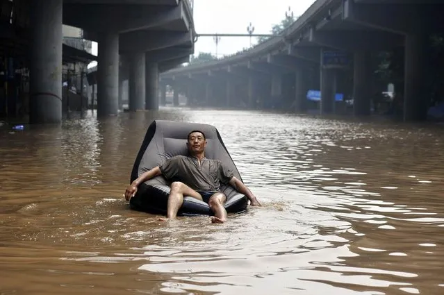 A man sits on an inflatable sofa floating on a flooded street near the Yangtze River in Chongqing, China, July 25, 2012. Torrential rain that battered 17 provinces since July 20 has left 95 dead and another 45 missing. (Photo by Shi Tou/Reuters)