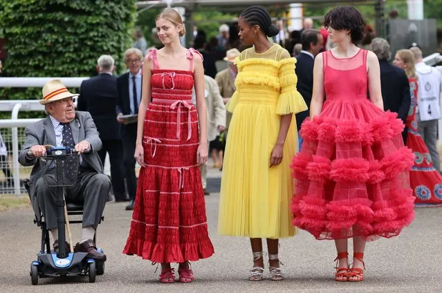 A man riding a mobility scooter gate crashes a fashion shoot with models wearing designer dresses as he rides past them unaware of the photographers they are posing for on the first day of the Goodwood Festival of Speed on June 26, 2022 in London, England. (Photo by Richard Pohle/The Times)