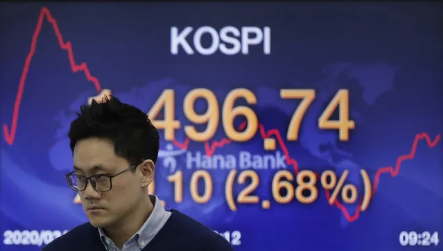 A currency trader walks by a screen showing the Korea Composite Stock Price Index (KOSPI) at the foreign exchange dealing room in Seoul, South Korea, Friday, March 20, 2020. Asian stock markets were mostly higher Friday after modest Wall Street gains on hopes government and central bank action can shield the world economy from a looming global recession caused by the coronavirus pandemic. (Photo by Lee Jin-man/AP Photo)